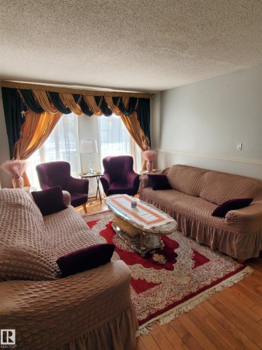 Warm living space featuring wood-finish flooring, light-colored walls, and a textured ceiling - 11814 157 Avenue, Edmonton, AB - Indoor Photo Showing Living Room
