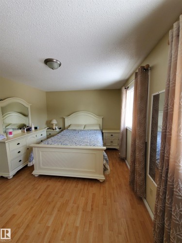 Spacious room featuring wood-finish flooring, a window providing natural light, and a ceiling-mounted light fixture - 11814 157 Avenue, Edmonton, AB - Indoor Photo Showing Bedroom