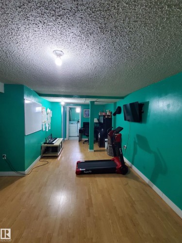 Spacious room with wood-finish flooring and vibrant teal walls - 11814 157 Avenue, Edmonton, AB - Indoor