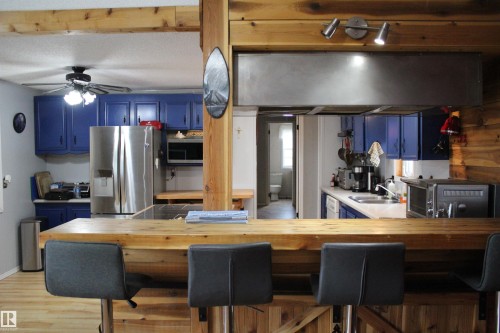 Kitchen featuring blue cabinetry, stainless steel appliances, and a wood-finish breakfast bar - 4839 49 Avenue, Chipman, AB - Indoor