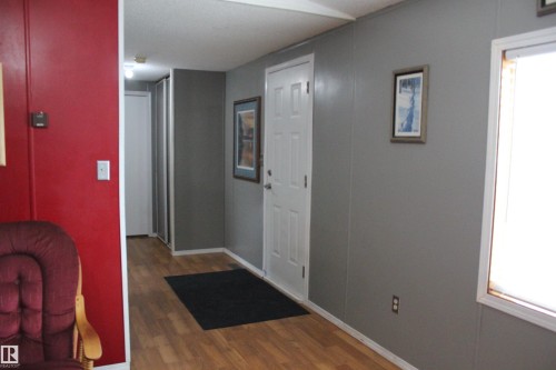 Entryway featuring light wood-finish flooring, a white paneled door, and neutral gray wall panels - 4839 49 Avenue, Chipman, AB - Indoor Photo Showing Other Room