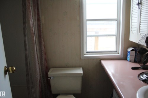 Bathroom featuring a window, pink countertop, and white cabinetry with louvered doors - 4839 49 Avenue, Chipman, AB - Indoor Photo Showing Bathroom