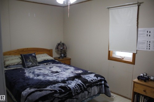 Neutral-toned wall paneling with wood trim, featuring a single window with a roller shade - 4839 49 Avenue, Chipman, AB - Indoor Photo Showing Bedroom