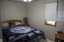 Neutral-toned wall paneling with wood trim, featuring a single window with a roller shade - 4839 49 Avenue, Chipman, AB  - Indoor Photo Showing Bedroom 