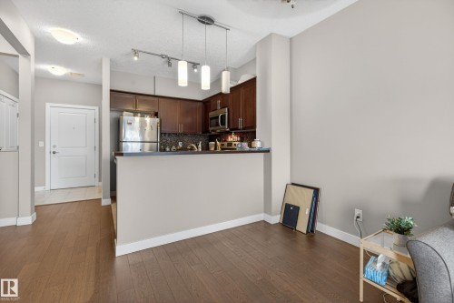 Kitchen with wood-finish cabinetry, stainless steel appliances, and a mosaic tile backsplash - 409 2584 Anderson Way, Edmonton, AB - Indoor Photo Showing Kitchen