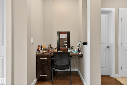 Dedicated nook featuring a dark wood-finish vanity with drawer storage, a wall-mounted shelf, and wood-finish flooring - 409 2584 Anderson Way, Edmonton, AB - Indoor