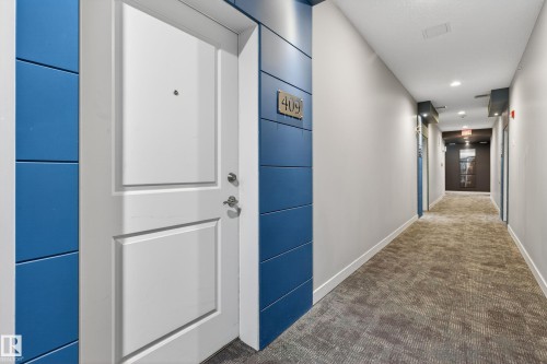 White paneled door with brushed nickel hardware, flanked by blue accent paneling - 409 2584 Anderson Way, Edmonton, AB - Indoor Photo Showing Other Room