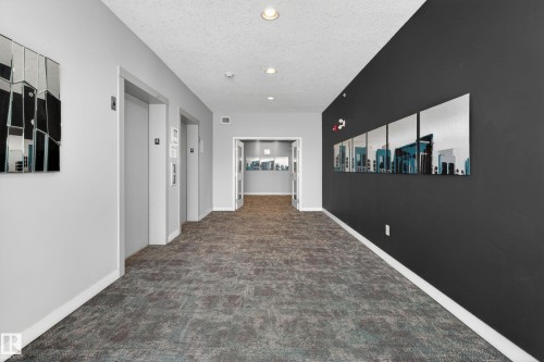 Hallway featuring durable carpet flooring, recessed lighting, and a modern color palette with accent wall - 409 2584 Anderson Way, Edmonton, AB - Indoor Photo Showing Other Room