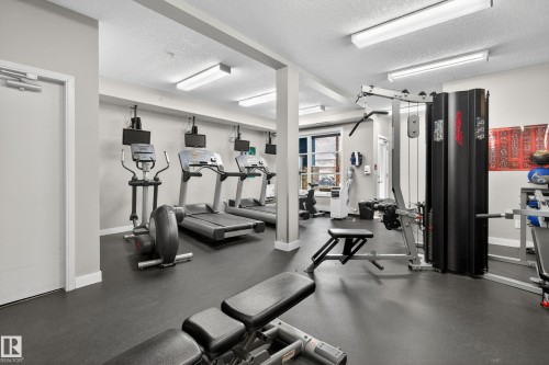 Fitness center with rubber flooring, recessed lighting, and multiple cardio machines - 409 2584 Anderson Way, Edmonton, AB - Indoor Photo Showing Gym Room