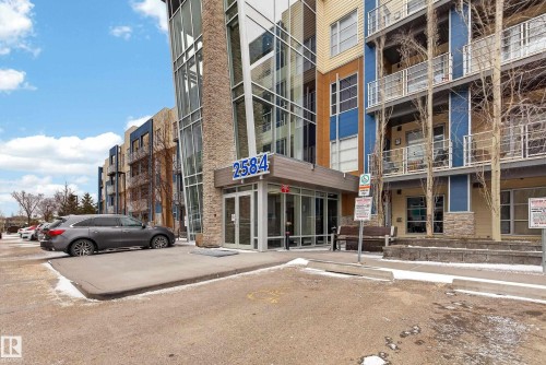 Modern multi-story building featuring stone veneer accents and a glass facade - 409 2584 Anderson Way, Edmonton, AB - Outdoor With Balcony With Facade