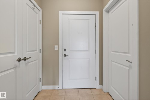 Entryway featuring a white paneled door with a peephole, flanked by two additional white paneled doors - 409 2584 Anderson Way, Edmonton, AB - Indoor Photo Showing Other Room