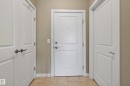 Entryway featuring a white paneled door with a peephole, flanked by two additional white paneled doors - 409 2584 Anderson Way, Edmonton, AB  - Indoor Photo Showing Other Room 