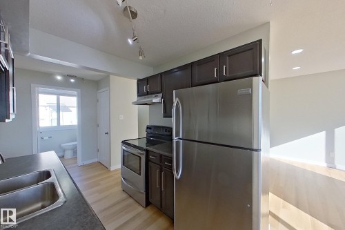 The kitchen features stainless steel appliances, dark cabinetry, and light-toned flooring - 184 Cornell Court, Edmonton, AB - Indoor Photo Showing Kitchen With Double Sink