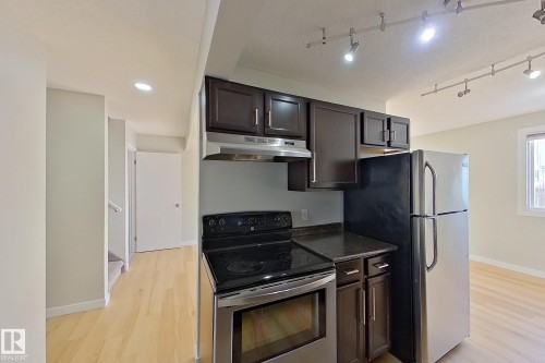 Kitchen featuring dark wood cabinets, granite countertops, and stainless steel appliances, including a refrigerator, range, and range hood - 184 Cornell Court, Edmonton, AB - Indoor Photo Showing Kitchen