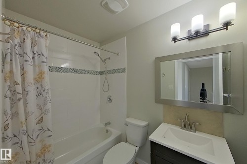 The bathroom features a vanity with a white countertop and a rectangular sink, a mirrored medicine cabinet, and a three-light fixture - 184 Cornell Court, Edmonton, AB - Indoor Photo Showing Bathroom