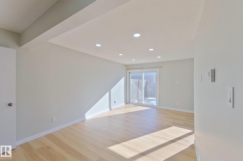 The living area features light-colored flooring, recessed lighting, and a sliding glass door leading to the exterior - 184 Cornell Court, Edmonton, AB - Indoor Photo Showing Other Room