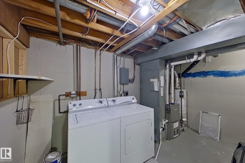 The property includes a laundry area with a washing machine and dryer, along with visible utility pipes and overhead structural beams - 184 Cornell Court, Edmonton, AB - Indoor