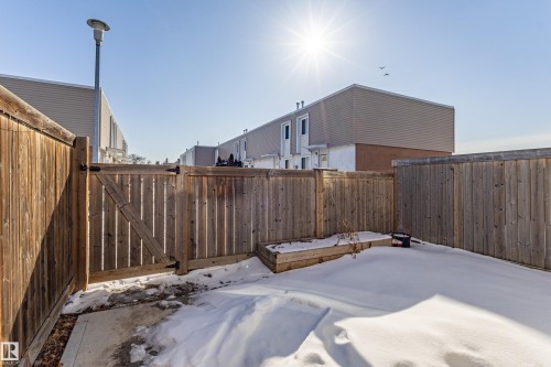 The property includes a fenced backyard with a wooden gate, a raised garden bed, and a concrete patio section - 184 Cornell Court, Edmonton, AB - Outdoor With Exterior