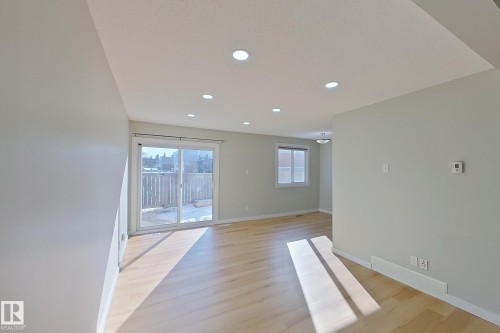 This bright living space features hardwood floors, recessed lighting, and a sliding glass door leading to an outdoor area - 184 Cornell Court, Edmonton, AB - Indoor Photo Showing Other Room
