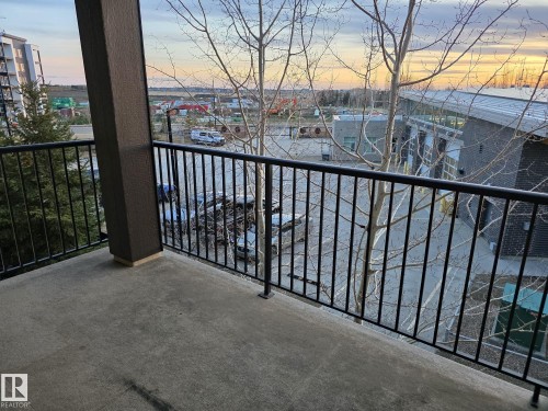 Concrete balcony featuring a black metal railing and a structural column - 310 12045 22 Avenue, Edmonton, AB 