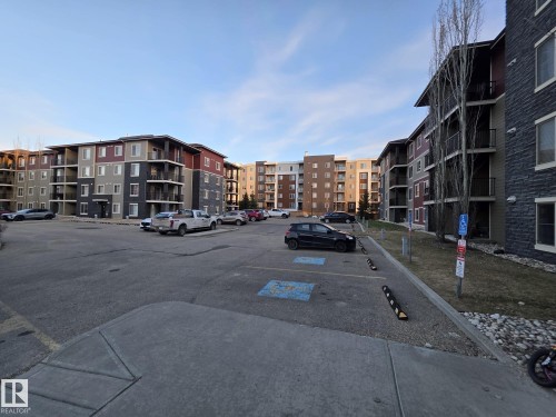 Apartment building exterior featuring multi-story construction, individual balconies, and a paved parking area - 310 12045 22 Avenue, Edmonton, AB 