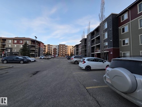 Multi-story residential buildings featuring varied siding materials including dark panels, red accents, and sage green panels - 310 12045 22 Avenue, Edmonton, AB 