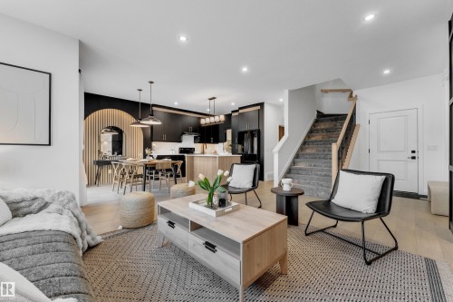 The open concept living area features light-colored flooring, recessed lighting, and a prominent staircase with a dark banister - 1089 Starling Drive, Edmonton, AB - Indoor Photo Showing Living Room
