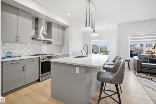 Modern kitchen featuring light wood-finish flooring and grey cabinetry - 7782 174A Avenue, Edmonton, AB - Indoor Photo Showing Kitchen With Double Sink With Upgraded Kitchen
