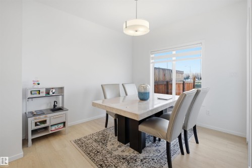 Bright dining area featuring light wood-finish flooring and a contemporary overhead light fixture - 7782 174A Avenue, Edmonton, AB - Indoor Photo Showing Dining Room