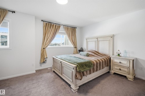 Spacious bedroom featuring neutral wall paint, carpet flooring, a ceiling-mounted light fixture, and two windows - 7782 174A Avenue, Edmonton, AB - Indoor Photo Showing Bedroom