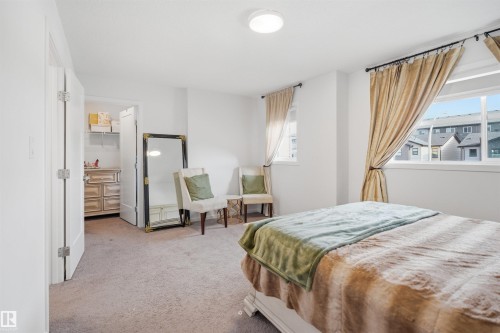 Carpeted room featuring a ceiling-mounted light fixture, multiple windows, and an open closet with built-in shelving - 7782 174A Avenue, Edmonton, AB - Indoor Photo Showing Bedroom