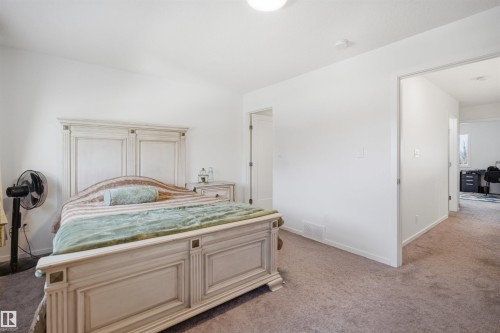 Carpeted room with white walls, featuring an open doorway revealing a second room with a window and carpeted flooring - 7782 174A Avenue, Edmonton, AB - Indoor Photo Showing Bedroom