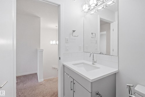 Bathroom vanity featuring a single basin sink with chrome faucet, a white countertop, and subway tile backsplash - 7782 174A Avenue, Edmonton, AB - Indoor Photo Showing Bathroom
