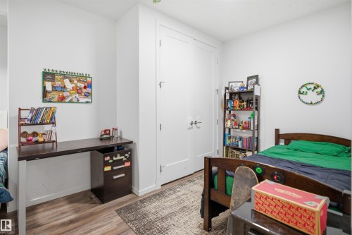 Interior room featuring wood-finish flooring, white walls, and a built-in desk with an integrated filing cabinet - 7782 174A Avenue, Edmonton, AB - Indoor Photo Showing Bedroom