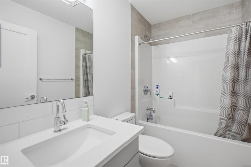 Bathroom featuring a vanity with an integrated sink, chrome-finish faucet, and a large wall-mounted mirror - 7782 174A Avenue, Edmonton, AB - Indoor Photo Showing Bathroom