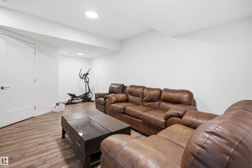Spacious room featuring wood-finish flooring, recessed lighting, and a white paneled door with contemporary hardware - 7782 174A Avenue, Edmonton, AB - Indoor Photo Showing Living Room