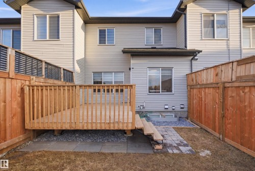 Private backyard featuring a wooden deck with railing, a stone patio, and perimeter fencing - 7782 174A Avenue, Edmonton, AB - Outdoor With Exterior