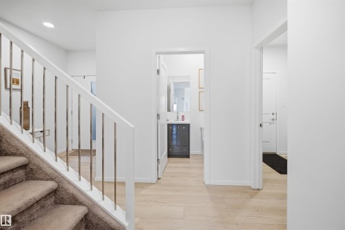Staircase with carpeted treads and white railing featuring metal balusters - 7782 174A Avenue, Edmonton, AB - Indoor Photo Showing Other Room
