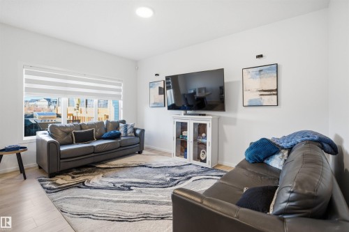Spacious living area featuring light wood-finish flooring, recessed lighting, and a large window with horizontal blinds - 7782 174A Avenue, Edmonton, AB - Indoor Photo Showing Living Room