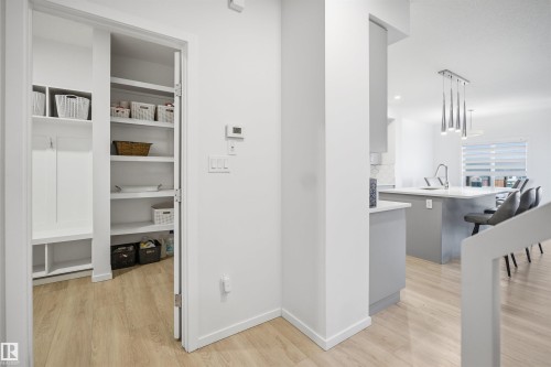 Mudroom featuring built-in storage, wood-finish flooring, and a pantry with shelving - 7782 174A Avenue, Edmonton, AB - Indoor