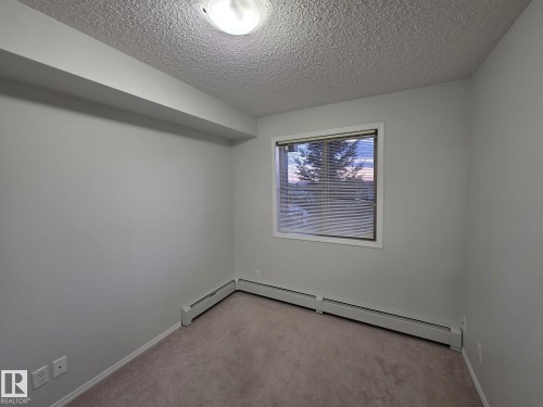 Neutral wall paint with baseboard trim - 206 12045 22 Avenue, Edmonton, AB - Indoor Photo Showing Other Room