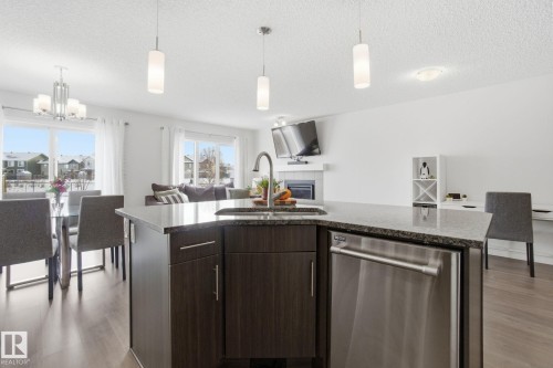 Open concept living space featuring a kitchen island with a stainless steel dishwasher, an integrated sink, and granite countertops - 2553 Coughlan Road, Edmonton, AB - Indoor Photo Showing Kitchen With Upgraded Kitchen