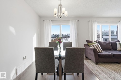 This room features a modern chandelier, hardwood style flooring, and large windows that provide natural light - 2553 Coughlan Road, Edmonton, AB - Indoor