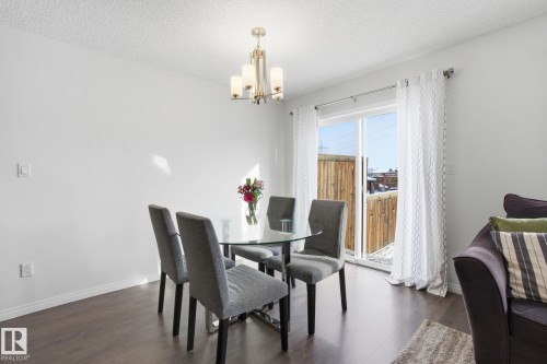 Dining area with dark wood flooring, a glass-top table, and a sliding glass door leading to the exterior - 2553 Coughlan Road, Edmonton, AB - Indoor Photo Showing Dining Room