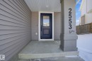 The property features a front entrance with a dark blue door, white trim, and light grey siding - 2553 Coughlan Road, Edmonton, AB  - Outdoor With Exterior 