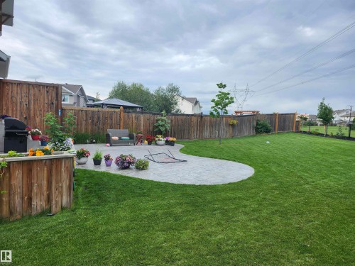 The property features an extensive yard with a well-maintained lawn and a large paved patio area - 2553 Coughlan Road, Edmonton, AB - Outdoor With Backyard