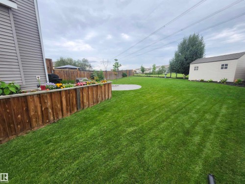 The property features an extensive, well-maintained lawn with a circular patio area - 2553 Coughlan Road, Edmonton, AB - Outdoor