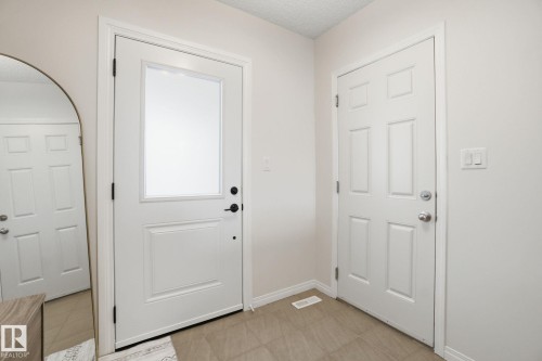 Foyer with light-colored walls, tile flooring, and two paneled doors with white trim - 2553 Coughlan Road, Edmonton, AB - Indoor Photo Showing Other Room