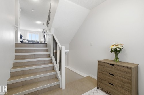 The property features a staircase with tile steps and white risers, leading to a living area with a large window - 2553 Coughlan Road, Edmonton, AB - Indoor Photo Showing Other Room
