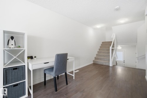 Bright interior space featuring wood-look flooring and white walls, with a carpeted staircase - 2553 Coughlan Road, Edmonton, AB - Indoor